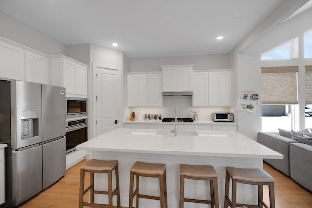 kitchen featuring stainless steel appliances, a center island with sink, and white cabinets