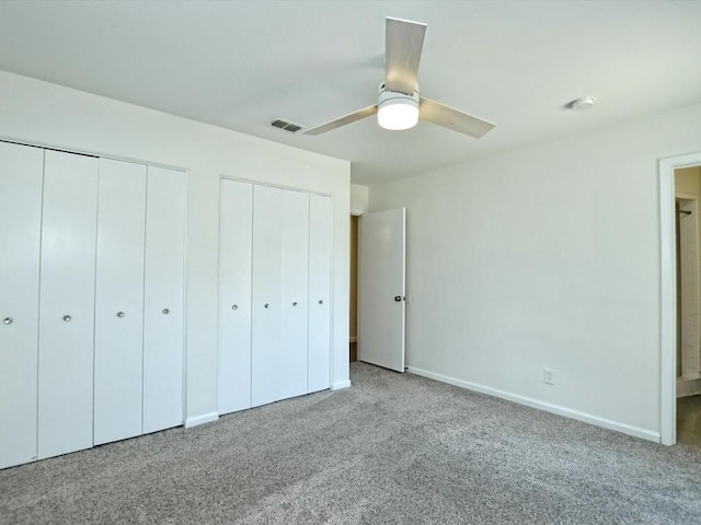 unfurnished bedroom featuring multiple closets, light colored carpet, and ceiling fan