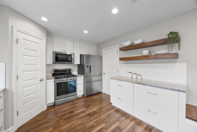 kitchen featuring appliances with stainless steel finishes, white cabinetry, dark hardwood / wood-style floors, tasteful backsplash, and light stone countertops