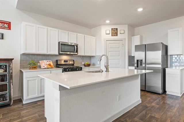 kitchen featuring stainless steel appliances, an island with sink, sink, and white cabinetry