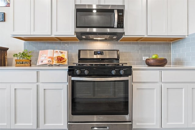 kitchen with stainless steel appliances, ventilation hood, white cabinets, and backsplash