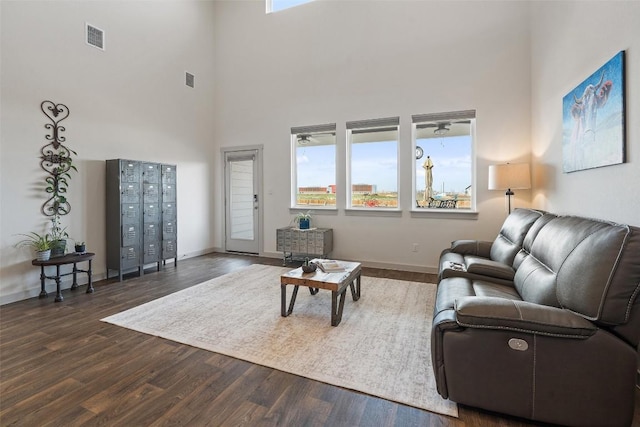 living room featuring dark wood-type flooring, a mail area, and a high ceiling