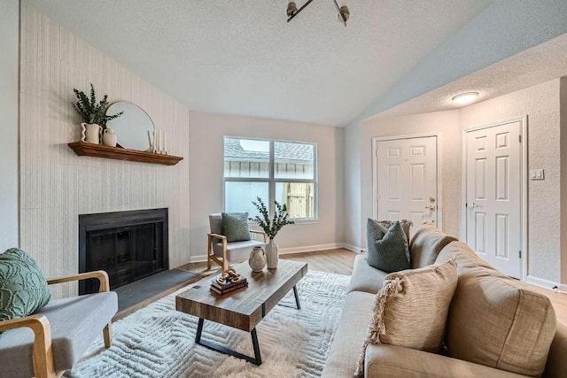 living room featuring vaulted ceiling, light hardwood / wood-style floors, and a textured ceiling