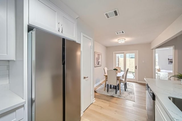 kitchen featuring white cabinetry, appliances with stainless steel finishes, light stone counters, and light hardwood / wood-style floors