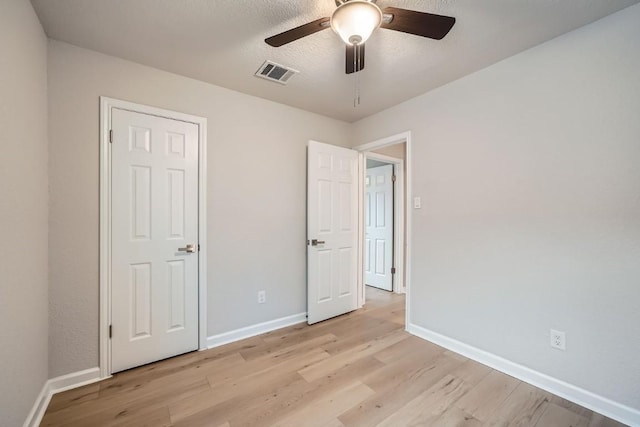 unfurnished bedroom featuring ceiling fan, a textured ceiling, and light hardwood / wood-style flooring