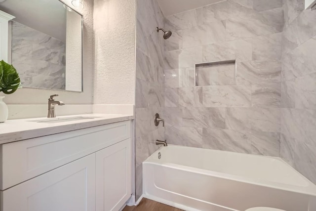 bathroom featuring tiled shower / bath and vanity