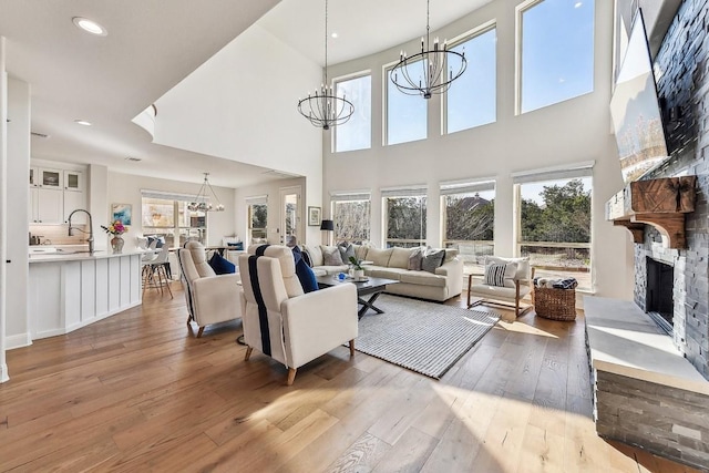 living room featuring a notable chandelier, light hardwood / wood-style flooring, a healthy amount of sunlight, and a fireplace