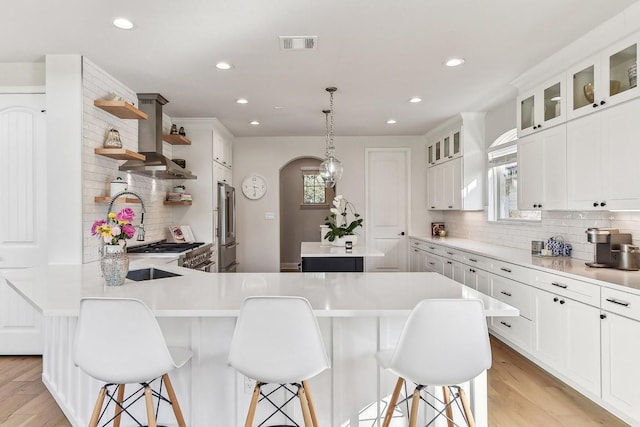 kitchen with white cabinetry, light wood-type flooring, island exhaust hood, and a kitchen breakfast bar