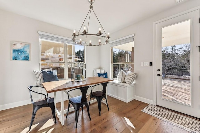 dining space with hardwood / wood-style flooring and an inviting chandelier