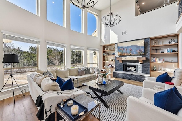 living room featuring hardwood / wood-style floors, a chandelier, and a stone fireplace