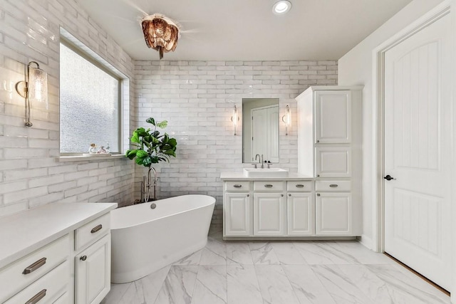 bathroom featuring brick wall, vanity, and a washtub