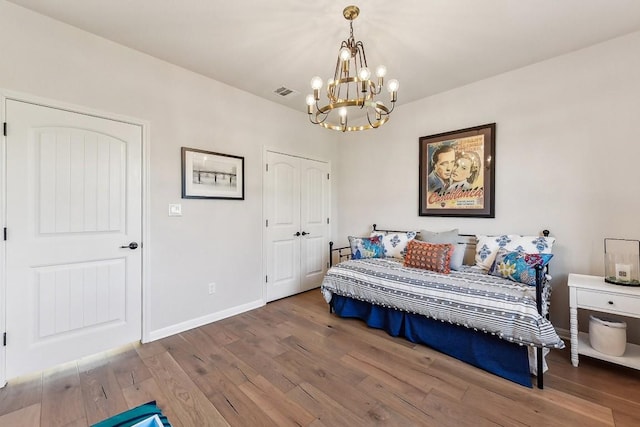 bedroom featuring an inviting chandelier, wood-type flooring, and a closet