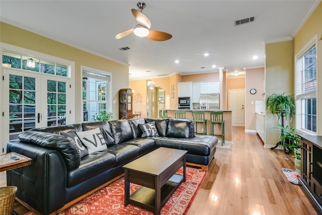 living room with crown molding, light hardwood / wood-style flooring, french doors, and ceiling fan