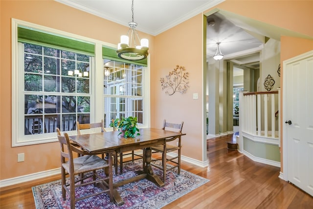 dining space with hardwood / wood-style flooring, crown molding, and an inviting chandelier