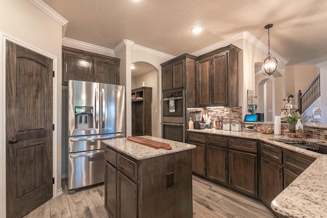 kitchen featuring pendant lighting, appliances with stainless steel finishes, a center island, and light stone countertops