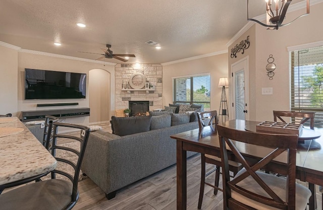 living room with wood-type flooring, ornamental molding, a textured ceiling, and a fireplace