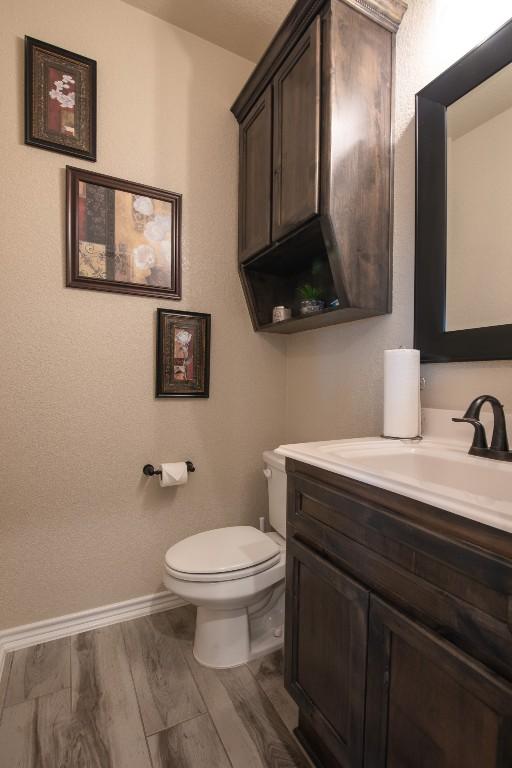 bathroom with vanity, toilet, and hardwood / wood-style floors