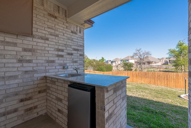 exterior space with sink, stainless steel fridge, and brick wall