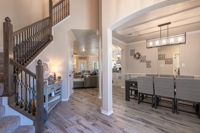 foyer with hardwood / wood-style floors, ornamental molding, a textured ceiling, and a high ceiling