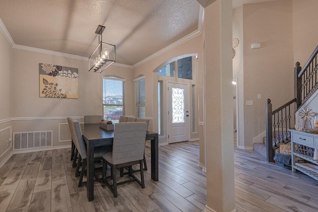 dining room with an inviting chandelier, ornamental molding, a textured ceiling, and light wood-type flooring