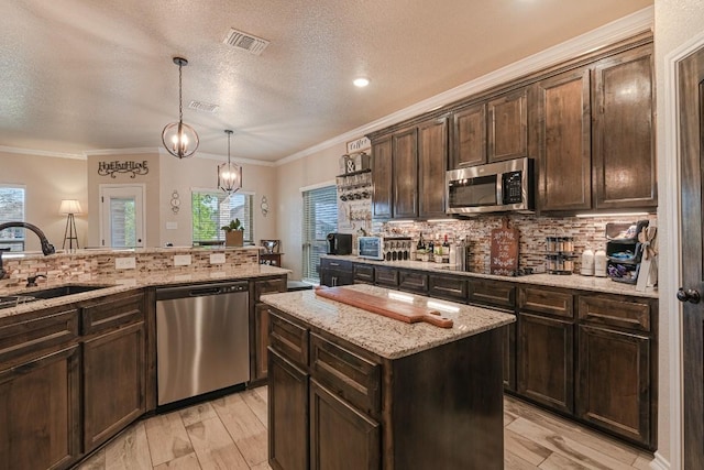 kitchen with dark brown cabinetry, sink, appliances with stainless steel finishes, a kitchen island, and pendant lighting