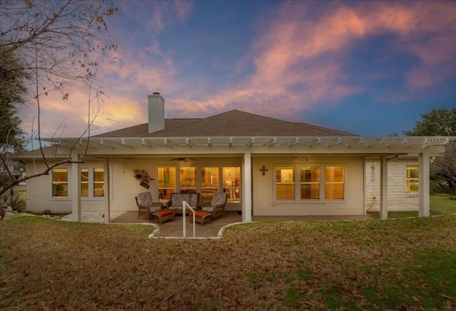 back house at dusk with outdoor lounge area, a yard, and a patio area