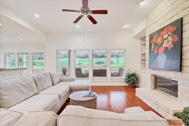 living room featuring a healthy amount of sunlight, light hardwood / wood-style floors, ornamental molding, and a fireplace