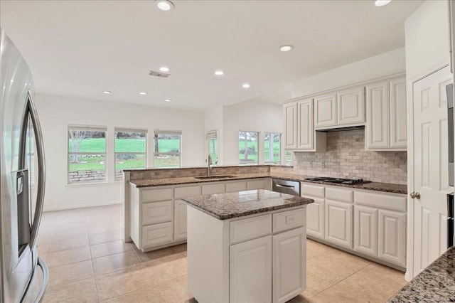 kitchen with a center island, appliances with stainless steel finishes, white cabinets, stone countertops, and decorative backsplash