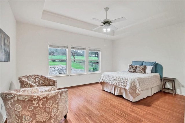 bedroom featuring a tray ceiling, ceiling fan, and wood-type flooring