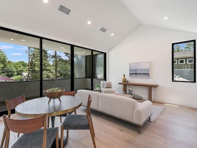 dining space with light wood-type flooring, vaulted ceiling, and a wealth of natural light