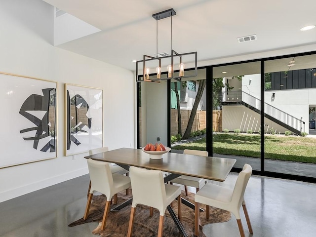 dining room with concrete flooring, floor to ceiling windows, and an inviting chandelier