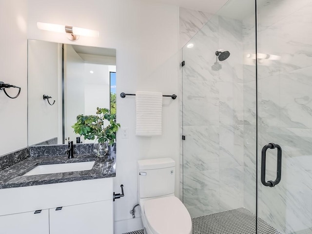 bathroom with vanity, a shower with door, and toilet