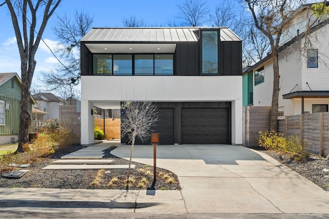 modern home featuring concrete driveway, metal roof, an attached garage, a standing seam roof, and board and batten siding