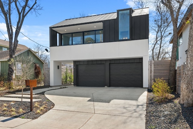 modern home featuring concrete driveway, an attached garage, fence, board and batten siding, and stucco siding