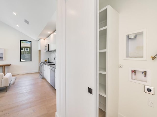 2903 E 14th St Unit 1, Austin, TX 78702 - kitchen with appliances with stainless steel finishes, white cabinetry, light wood-style floors, backsplash, and vaulted ceiling