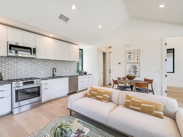 2903 E 14th St Unit 1, Austin, TX 78702 - kitchen with stainless steel appliances, a sink, light wood finished floors, tasteful backsplash, and white cabinetry