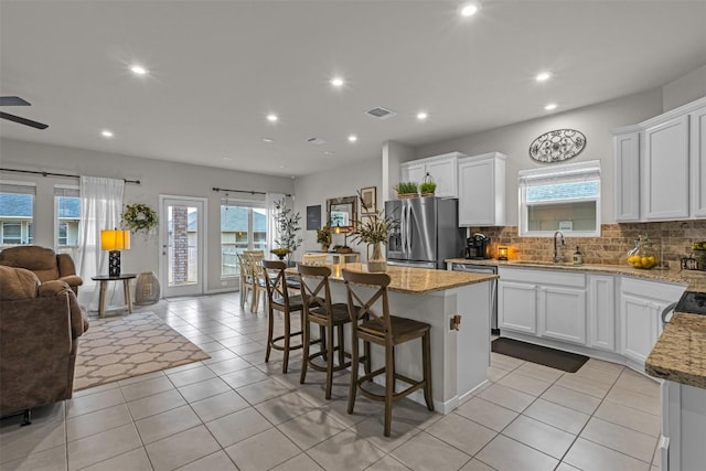 2221 Clove Ct, Temple, TX 76501 - kitchen with white cabinetry, a center island, a kitchen bar, and stainless steel fridge with ice dispenser