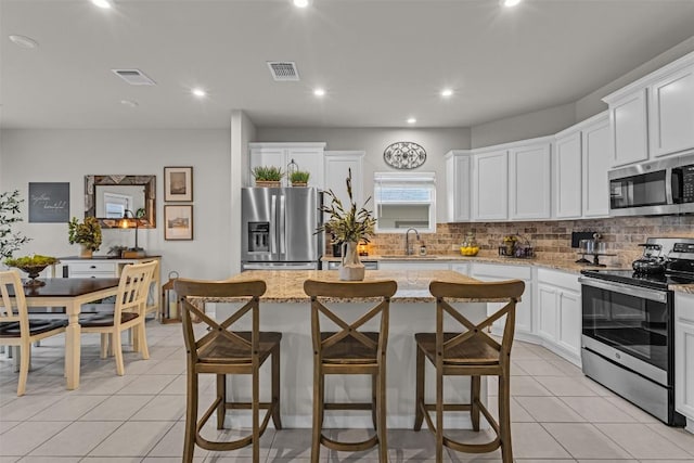 2221 Clove Ct, Temple, TX 76501 - kitchen featuring light stone counters, a center island, white cabinets, and appliances with stainless steel finishes