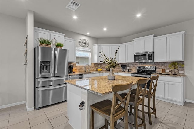 2221 Clove Ct, Temple, TX 76501 - kitchen featuring sink, stainless steel appliances, a center island, light stone counters, and white cabinets
