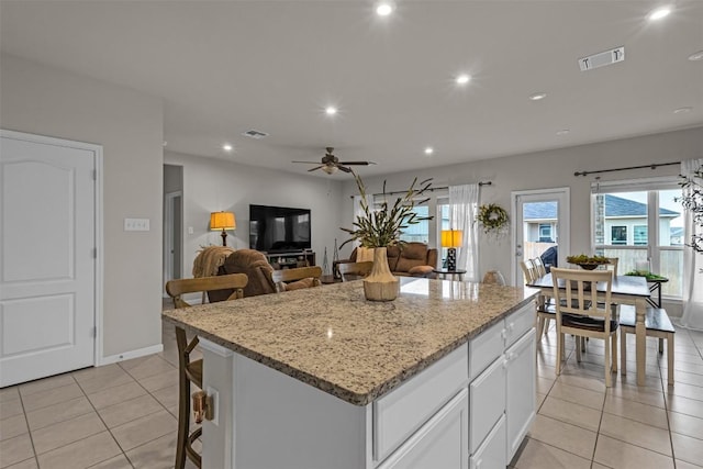 2221 Clove Ct, Temple, TX 76501 - kitchen with light tile patterned floors, ceiling fan, light stone countertops, white cabinets, and a kitchen island