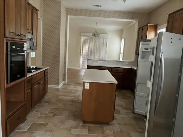 103 Wild Rose Dr, Georgetown, TX 78633 - kitchen featuring stainless steel appliances, wallpapered walls, a kitchen island, light countertops, and light stone finish floors