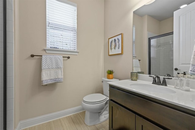 bathroom featuring a shower with door, vanity, and toilet