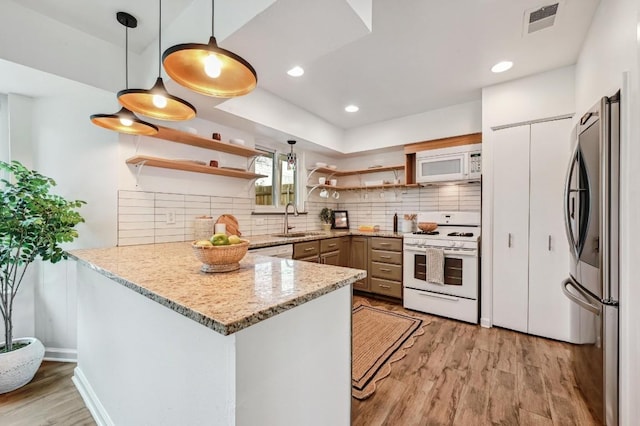 kitchen featuring sink, decorative light fixtures, kitchen peninsula, white appliances, and light hardwood / wood-style floors