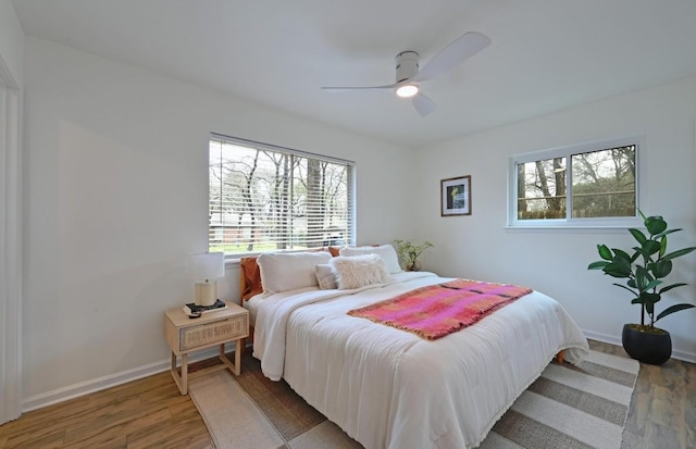 bedroom with ceiling fan, hardwood / wood-style floors, and multiple windows