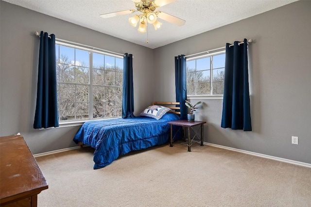 bedroom with ceiling fan, light colored carpet, and a textured ceiling