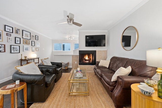 living room with a tile fireplace, hardwood / wood-style floors, crown molding, and ceiling fan