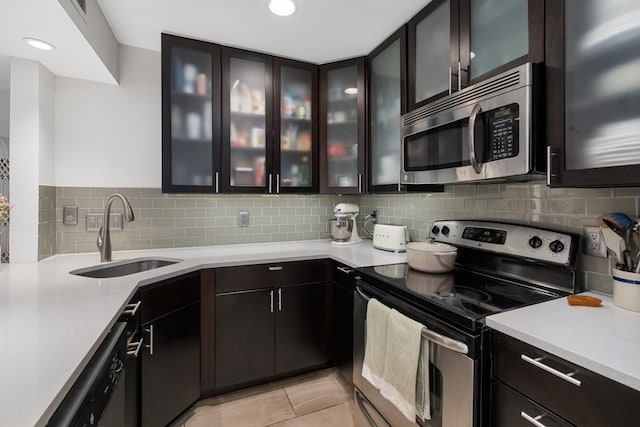 kitchen with appliances with stainless steel finishes, sink, dark brown cabinets, and tasteful backsplash