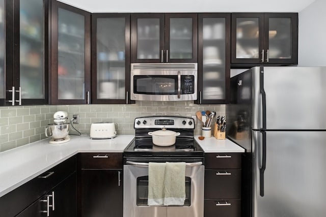 kitchen with dark brown cabinets, stainless steel appliances, and tasteful backsplash