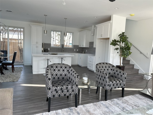 interior space with sink, tasteful backsplash, hanging light fixtures, dark hardwood / wood-style floors, and white cabinets