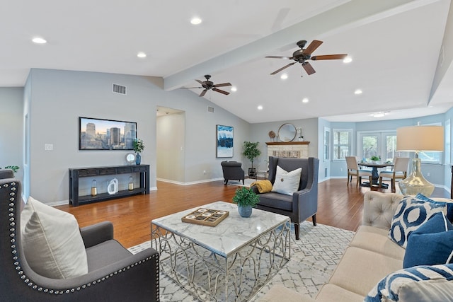 living room featuring ceiling fan, light wood-type flooring, and vaulted ceiling with beams